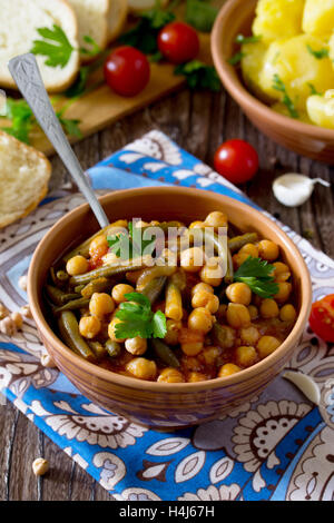 Gesunde Ernährung, Diät, vegetarische Küche und Koch-Konzept - geschmorte Kichererbsen mit Tomaten, Knoblauch und grünen Bohnen. Gekochte po Stockfoto