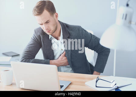 Hübscher junger Mann Kummer durch am Arbeitsplatz leiden. Stockfoto