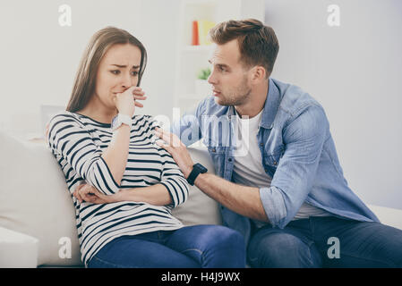 Junge hübsche Frau und gut aussehender Mann auf dem Sofa sitzen. Stockfoto