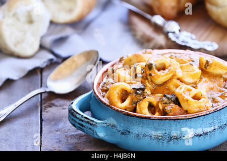 Tomaten und Spinat-Tortellini-Suppe mit frisch gebackenem Brot.  Extrem geringe Schärfentiefe. Stockfoto