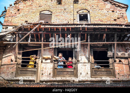 Kinder spielen an den Fenstern eines Hauses, das 2015 durch das Erdbeben in Bhaktapur, Nepal, zerstört wurde. Stockfoto