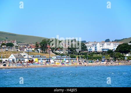 Urlauber am Strand und im Meer mit Wasser Gebäude nach hinten, Swanage, Dorset, England, Vereinigtes Königreich, West-Europa. Stockfoto