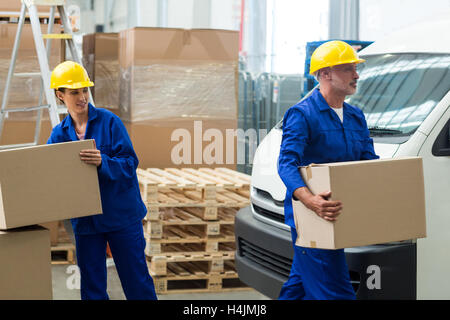 Lieferung Arbeiter entladen Kartons von Hubwagen Stockfoto