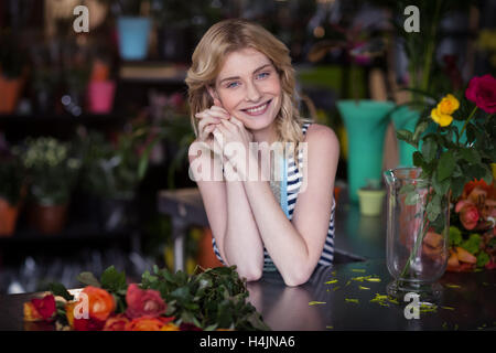 Glücklich weibliche Florist stützte sich im Blumenladen Stockfoto