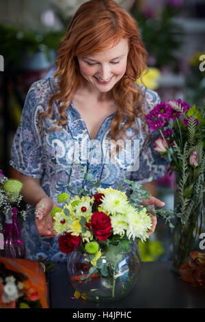 Weibliche Florist Prüfung ein Blumen-Arrangement in vase Stockfoto