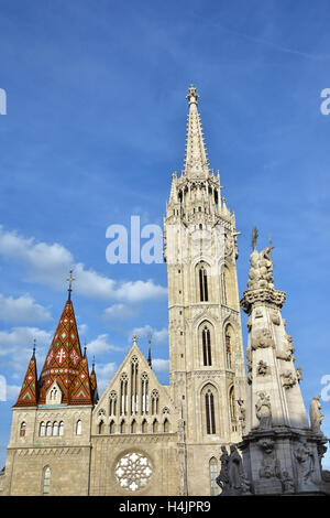 Matthias-Kirche, erbaut im schönen gotischen Stil in der historischen Innenstadt von Budapest, bei Sonnenuntergang mit Säule der Heiligen Dreifaltigkeit Stockfoto