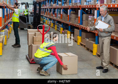 Warehouse Manager zeigt Daumen hoch für Arbeitnehmerin während des Tragens Kartons Stockfoto