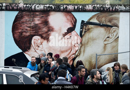 Touristen sind am kurz zu öffnende Zaun vor dem Bild fotografiert "Mein Gott, mir, diese tödliche Liebe zu überleben von Dmitri Vladimirovich Vrubel an der East Side Gallery in Berlin, Deutschland 16. Oktober 2016 zu helfen". Seit einigen Monaten das Denkmal an der ehemaligen innerdeutschen Grenze umfassend restauriert und zahlreiche Kunstwerke wurden restauriert. Der Zaun soll derzeit Besucher vor schädlichen bereits gereinigten Flächen zu verhindern. Die Kreisverwaltung Friedrichshain-Kreuzberg will das Kunstwerk auch nach seiner Fertigstellung zu schützen. Foto: Rainer Jensen/dpa Stockfoto