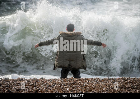 Brighton, UK. 16. Oktober 2016. Ein Mann riskiert sein eigenes Leben und dass jede mögliche Retter von wandernden ins Meer bei Flut und starkem Wind heute Morgen dort für mindestens zehn Minuten. Strandpromenade Offiziere waren aber der Mann alarmiert, die schien sich in einen Zustand der Euphorie, wanderte grinsend. Bildnachweis: Andrew Hasson/Alamy Live-Nachrichten Stockfoto