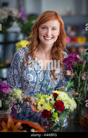 Weibliche Florist Prüfung ein Blumen-Arrangement in vase Stockfoto