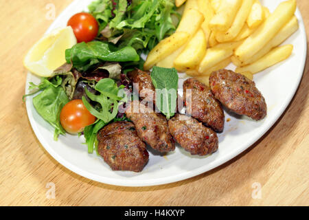 Gegrillte Frikadellen serviert mit Pommes Frites und Salat Stockfoto