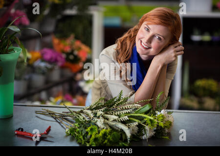 Glücklich weibliche Florist stützte sich im Blumenladen Stockfoto