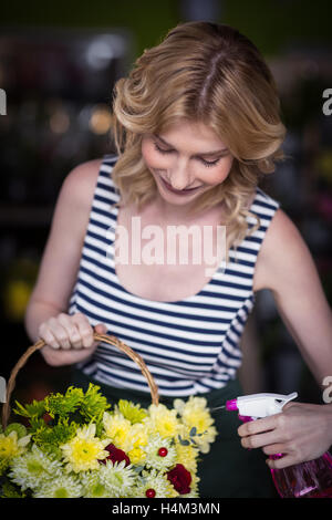 Weibliche Floristen Sprühwasser auf Blumen im Blumenladen Stockfoto