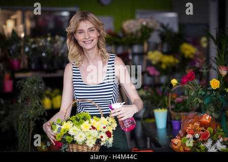 Weibliche Floristen Sprühwasser auf Blumen im Blumenladen Stockfoto