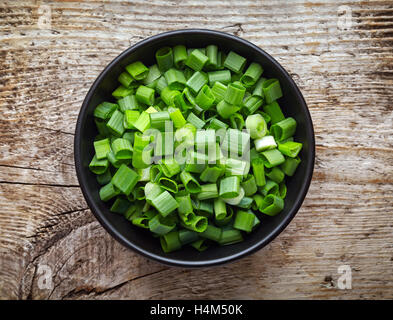 Schüssel mit gehackten Frühlingszwiebeln auf Holztisch, Ansicht von oben Stockfoto