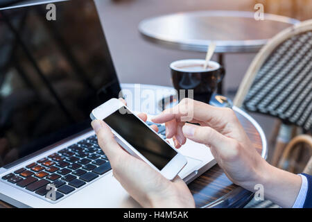 Reisende, die e-Mails mit Laptop und Smartphone während der Kaffeepause im freien Stockfoto