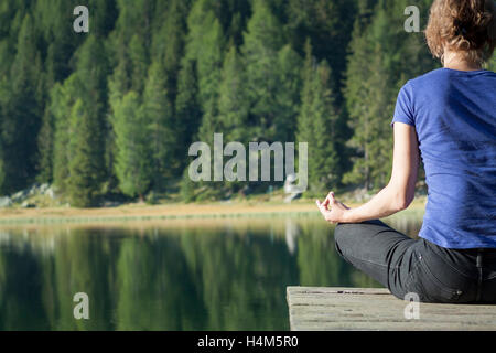 Hübsche Frau praktizieren Yoga am See Stockfoto