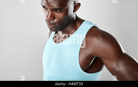 Schuss von Fit junger Mann muskulös steht vor grauem Hintergrund hautnah. Afro american Fitness Modell Wegsehen ein Stockfoto