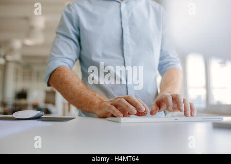 Nahaufnahme der Geschäftsmann Hände Tippen auf der Computertastatur. Zugeschnittenen Schuss junger Mann auf Computer im stehen an seinem Schreibtisch arbeiten Stockfoto