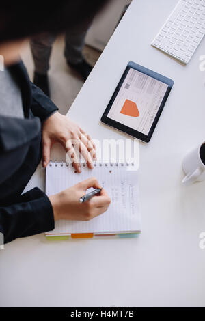 Draufsicht der weiblichen Vorstand Stand am Tisch mit digital-Tablette in Tagebuch zu schreiben. Geschäftsfrau Notizen im Editor. Stockfoto