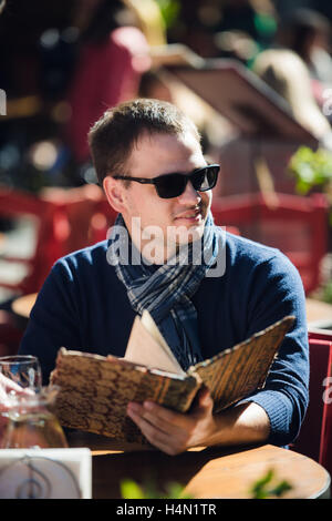 Cooler junger Mann in Sonnenbrille Bestellung etwas in einem Straßencafé Stockfoto