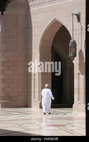 Ein Verehrer in traditionelle arabische Kleidung geht auf einem großen Bogen an der großen Moschee in Maskat, Oman Stockfoto