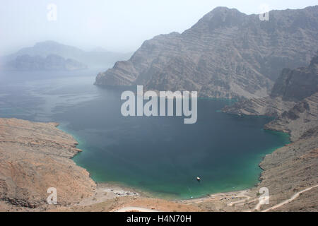 Die wilde Landschaft der Halbinsel Musandam in Khor ein Najd im nördlichen Oman.  Eine einzige Dhau ist in der Bucht vor Anker. Stockfoto