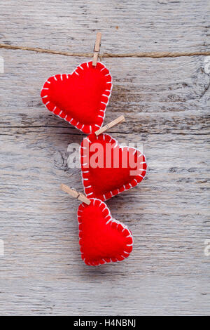 Rote Herzen hängen über grau Holz Hintergrund Stockfoto