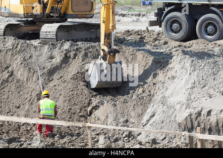 Arbeiter, Bagger Bagger und Lastwagen auf einer Baustelle. Erdarbeiten. Stockfoto