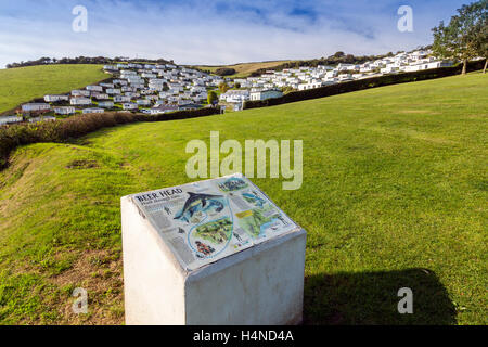 Eine Informationstafel und statische Caravan Park an Bier auf dem Küstenpfad SW und die Jurassic Coast South Devon, England, UK Stockfoto