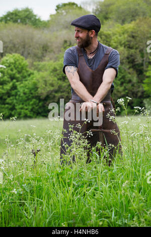 Der Mensch in eine Lederschürze, Stand in einem Feld mit einem Schwert. Stockfoto