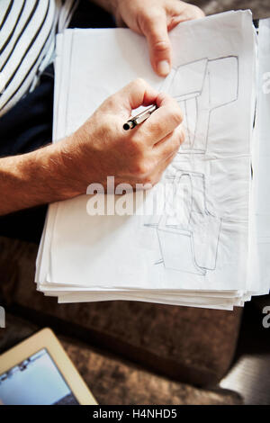 Ein Mann sitzt mit einem Stift und zeichnen von Skizzen, einen Designer bei der Arbeit. Stockfoto