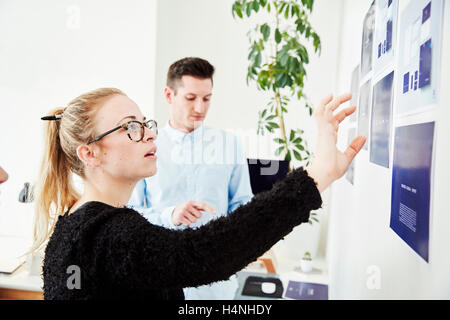 Zwei Personen an gedruckten Pläne fest an einer Wand, Projektmanagement und Diskussionen. Stockfoto