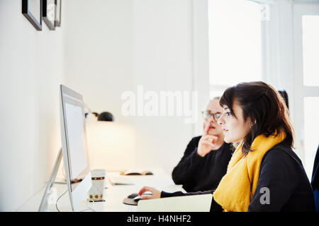 Zwei Frauen sitzen einen Computer-Bildschirm teilen und diskutieren die grafischen Inhalten. Stockfoto