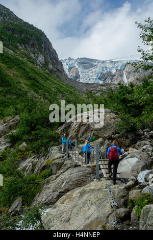 Tourist-Familie mit Kindern wandern über Felsen und Brücke zu den Buerbreen Gletscher Folgefonna Nationalpark, Norwegen Stockfoto