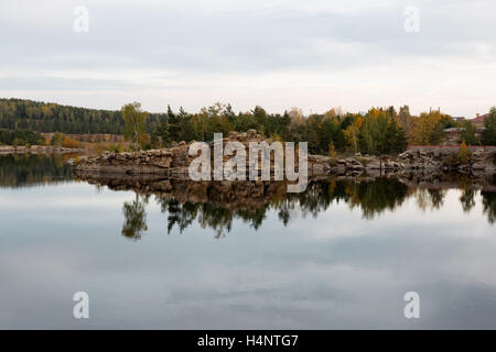 Stein im Herbst See mit Birke und Kiefer Stockfoto