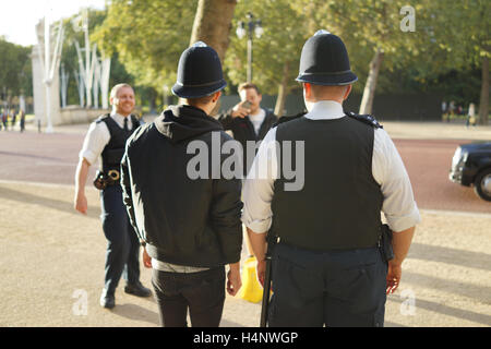 Freundliche Polizist verleiht seinen Hut ein Tourist in London Stockfoto