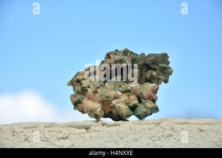 Grüne Mineralien Stein auf weiße Wand vor blauem Himmel Stockfoto