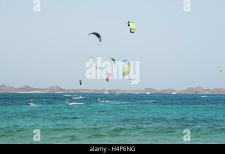 Fuerteventura, Kanarische Inseln, Nordafrika, Spanien: Kitesurfen am Strand von Grandes Playas mit der kleinen Insel Lobos, die auf dem Hintergrund Stockfoto