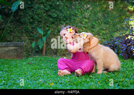 Lustiges Foto glückliches Baby umarmt schöne goldene Labrador Retriever Welpen. Mädchen spielen mit Hund. Stockfoto