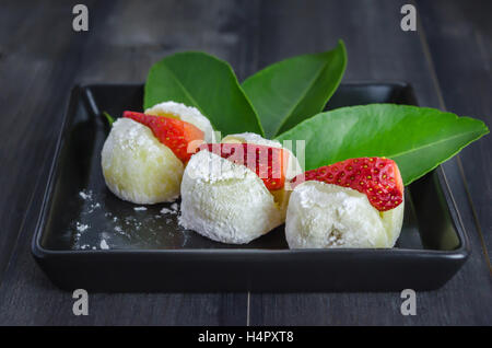 Erdbeere Daifuku Mochi japanisches Dessert auf schwarzem Teller über hölzerne Hintergrund Stockfoto