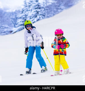Kinder beim Skifahren in Bergen. Aktive Kinder mit Helm, Schutzbrille und Polen. Skirennen für kleine Kinder. Wintersport Stockfoto