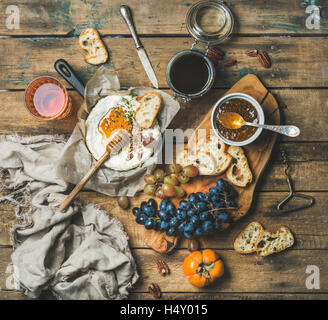Käse, Obst und Wein über rustikalen hölzernen Hintergrund festlegen Stockfoto