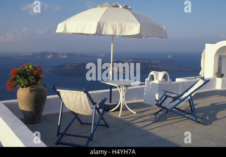 Tisch, Stühlen und einem Sonnenschirm auf der Terrasse einer Ferienwohnung mit Blick auf das Meer in Imerovigli, Santorin, Kykladen Stockfoto