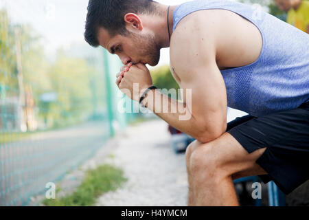 Fit kaukasischen Mann nachdenklich sitzen stützte sich auf seine Hände Stockfoto