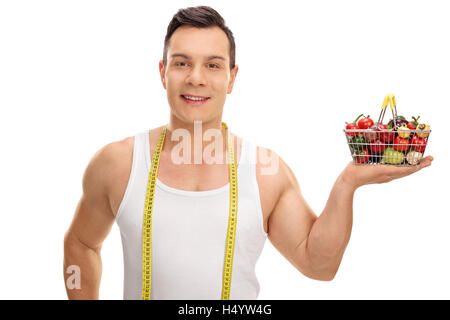 Hübscher junger Mann posiert mit einem Maßband und einen kleinen shopping Korb voller Früchte und Gemüse isoliert auf weißem Rücken Stockfoto