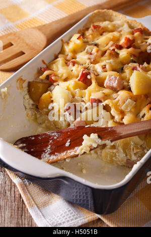 Französische Tartiflette Kartoffeln mit Speck und Käse hautnah in Auflaufform legen. vertikale Stockfoto