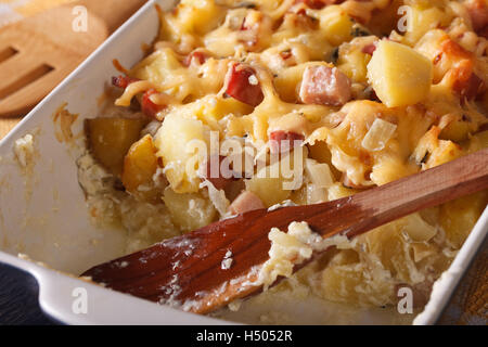 Französische Küche: Tartiflette Kartoffeln mit Speck und Käse hautnah in Auflaufform legen. Horizontale Stockfoto