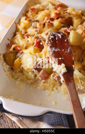 Französische Küche: Tartiflette Kartoffeln mit Speck und Käse hautnah in Auflaufform legen. vertikale Stockfoto