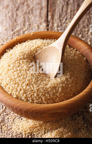 Den trockenen Couscous in einer Holzschale mit einer Nahaufnahme der Löffel auf dem Tisch. Vertikal Stockfoto